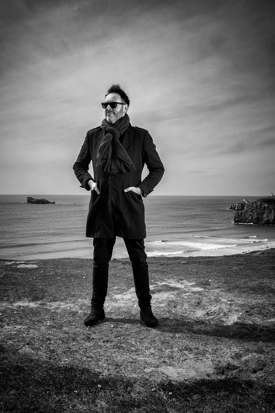 A black and white photogaphy of Robin Foster, standing a beach in what happens to be a cold winter morning